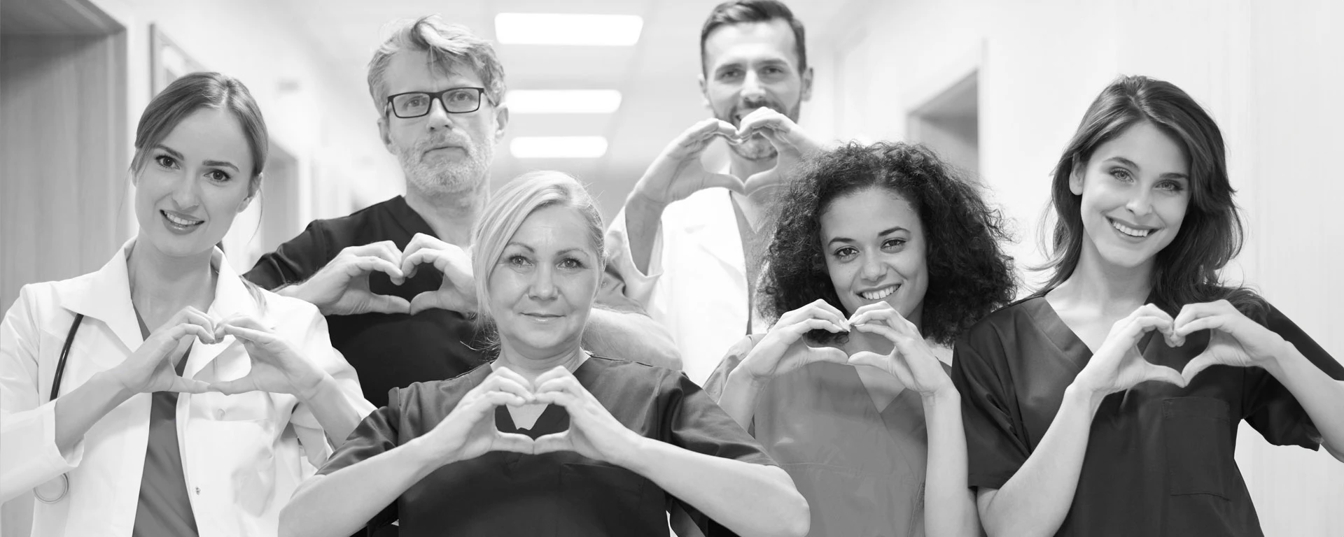 Medizinische Mitarbeiter in einer Klinik lächeln in die Kamera und machen ein Herz mit Ihren Händen - BAUER B+V Pflegedienst